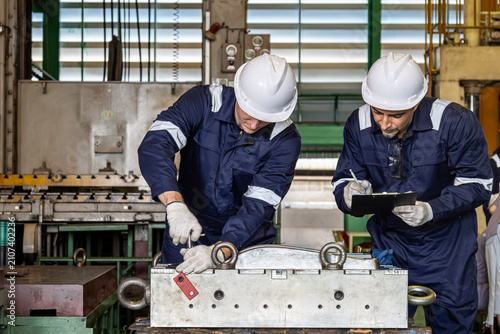 Foto Manual worker in protective uniform and helmet fixing machine