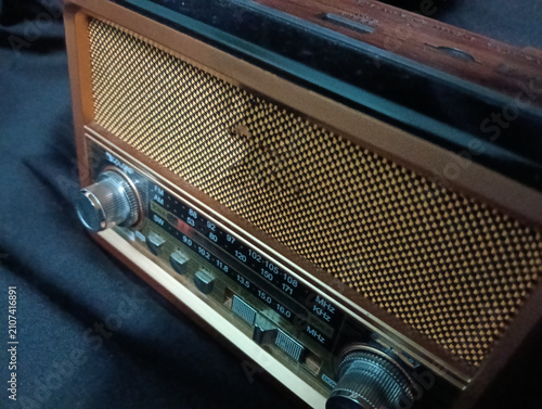 Foto A vintage portable analog radio with a classic wooden cabinet, woven speaker grille, and silver tuning knobs