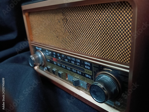 Fotografie A vintage portable analog radio with a classic wooden cabinet, woven speaker grille, and silver tuning knobs