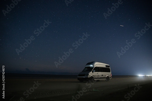 Campervan beneath a star-filled night sky on beach