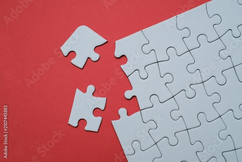 Konstfotografi White jigsaw puzzle with missing pieces separated on a red background