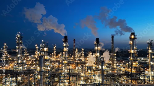 Aerial view of illuminated oil refinery at blue hour, petrochemical industry