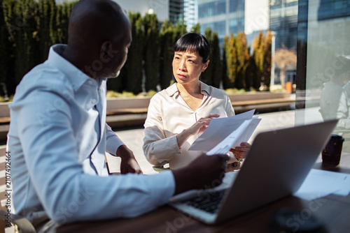 Two business colleagues reviewing documents on an outdoor office patio