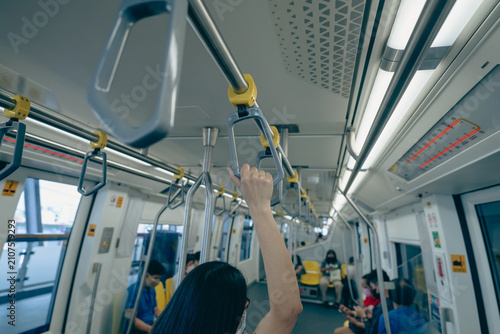Woman hand firm grip safety handrail in elevated monorail train. Mass transit system in modern city. Inside of electric train. Tourist travel by city sky train. Public transportation. Urban transport.