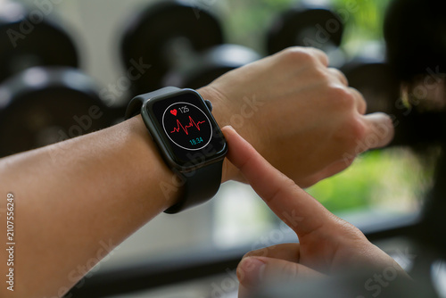Obraz na plátně Hand of woman using smartwatch to monitor heart rate and health data