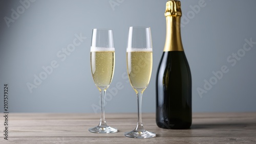 Champagne Celebration: Two flute glasses filled with sparkling champagne stand beside a gold-capped bottle, ready to toast a special occasion.