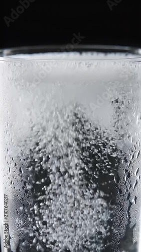 Fresh water pouring into clear glass with condensation.
