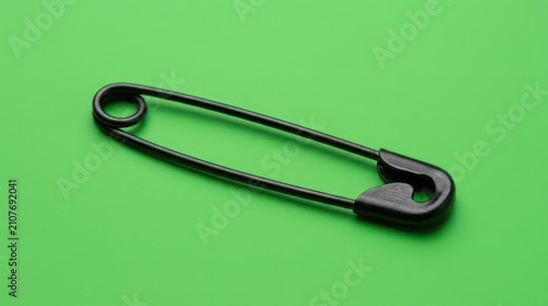 Black metal safety pin on green background