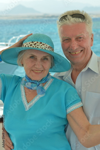 senior smiling and embracing in indoor setting with textile and fabric objects, close-up slightly tilted, blue and white colors, family portraits, senior lifestyle.