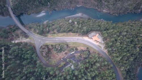 фотографія Beautiful drone landscape showing a winding mountain road beside a forest river from above