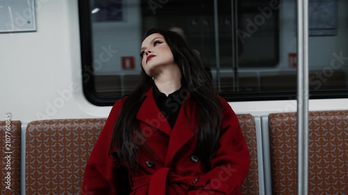 A stylish brunette in a scarlet coat riding a subway car, city rhythm