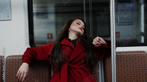 A stylish brunette in a scarlet coat riding a subway car, city rhythm