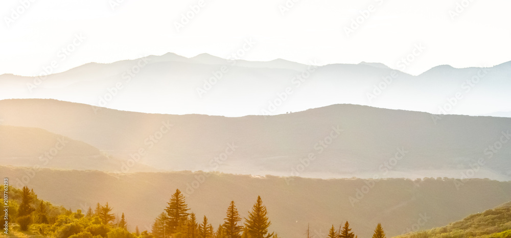 Obraz premium Golden sunrise over hazy mountain layers