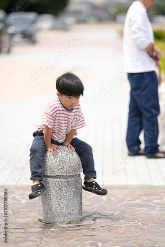 Photography Little boy sits atop stone bollard