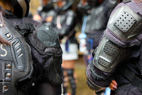 Armored protective gear and elbow pads on riders preparing for outdoor sports event, gritty texture and focused teamwork energy
