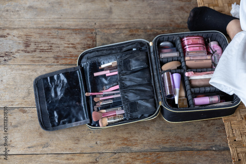 Foto Makeup brush and cosmetic kit open on wooden floor with soft natural light showi