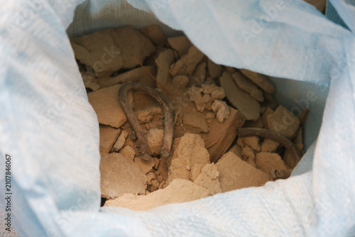 A close-up view of a bag filled with broken pieces of clay or plaster. The contents appear dusty and fragmented, showcasing a mix of textures and shapes.