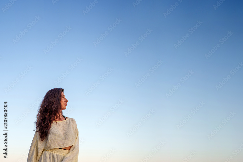 Obraz premium Woman with curly hair looking confidently towards new horizons, contemplating future under clear open blue sky