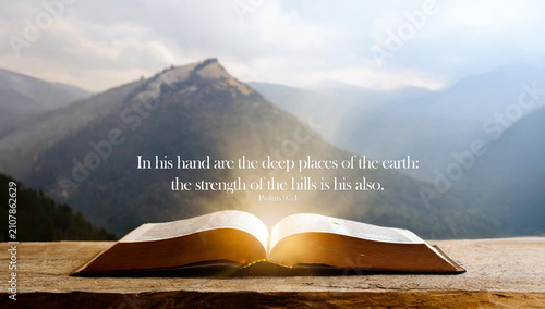 Open book Bible against the background of mountains. In His hand are the deep places of the earth: the strength of the hills is is also Psalms 95:4