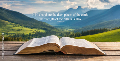 Open book Bible against the background of mountains. In His hand are the deep places of the earth: the strength of the hills is is also Psalms 95:4