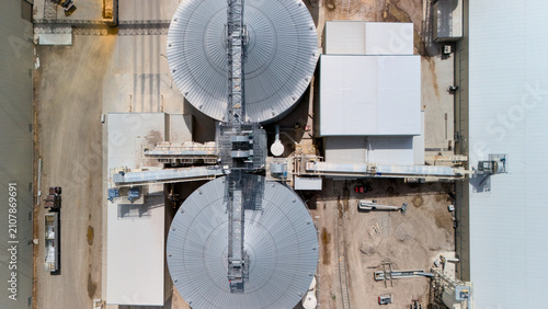 Tableau sur toile Top down aerial view of two large circular grain storage silos connected by catwalks