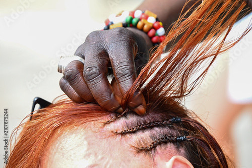 Foto Une femme avec des bracelets colorés fait des tresses  dans les cheveux d'une fe