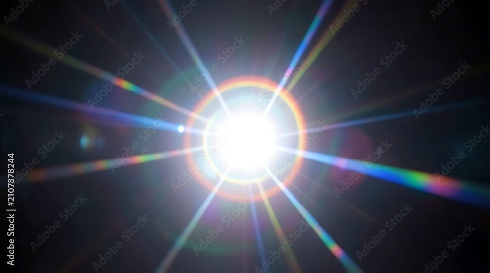 Obraz premium Bright sunburst with rainbow lens flare spreading rays across a clear sky.
