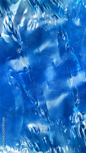 Abstract background of crumpled blue metallic foil texture with highlights and shadows