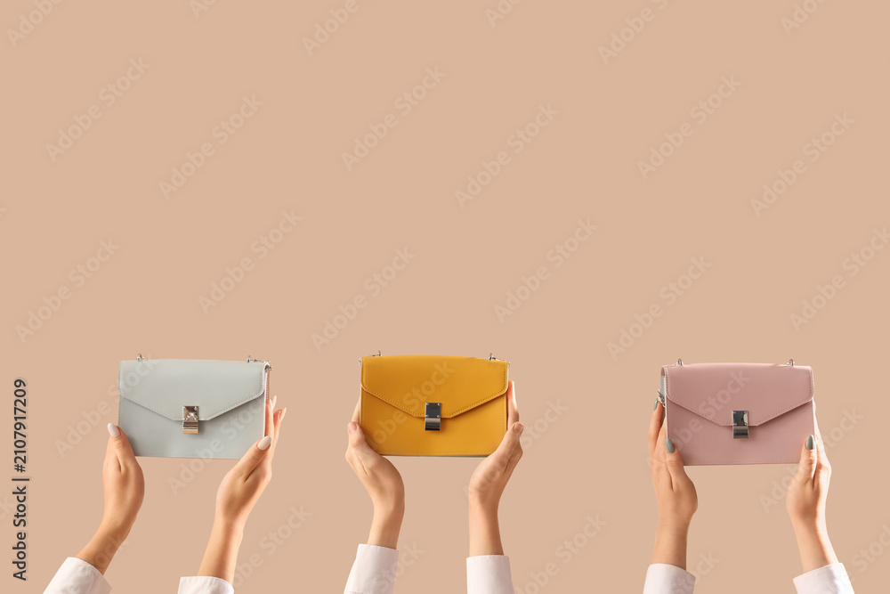 Fototapeta premium Female hands with different stylish womens bags on beige background
