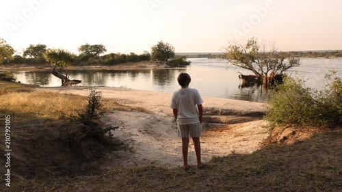 young man looking out at sunset on the mighty Zambezi River, Zambezi National Park, Zimbabwe, Africa