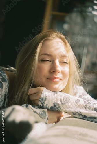 Happy blonde woman enjoying warm sunlight with closed eyes, peaceful morning moment on 35mm film