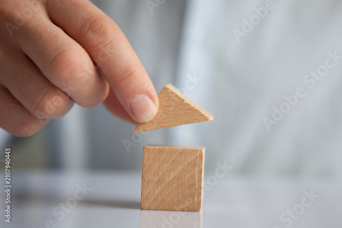 Man building up house with building blocks, close-up