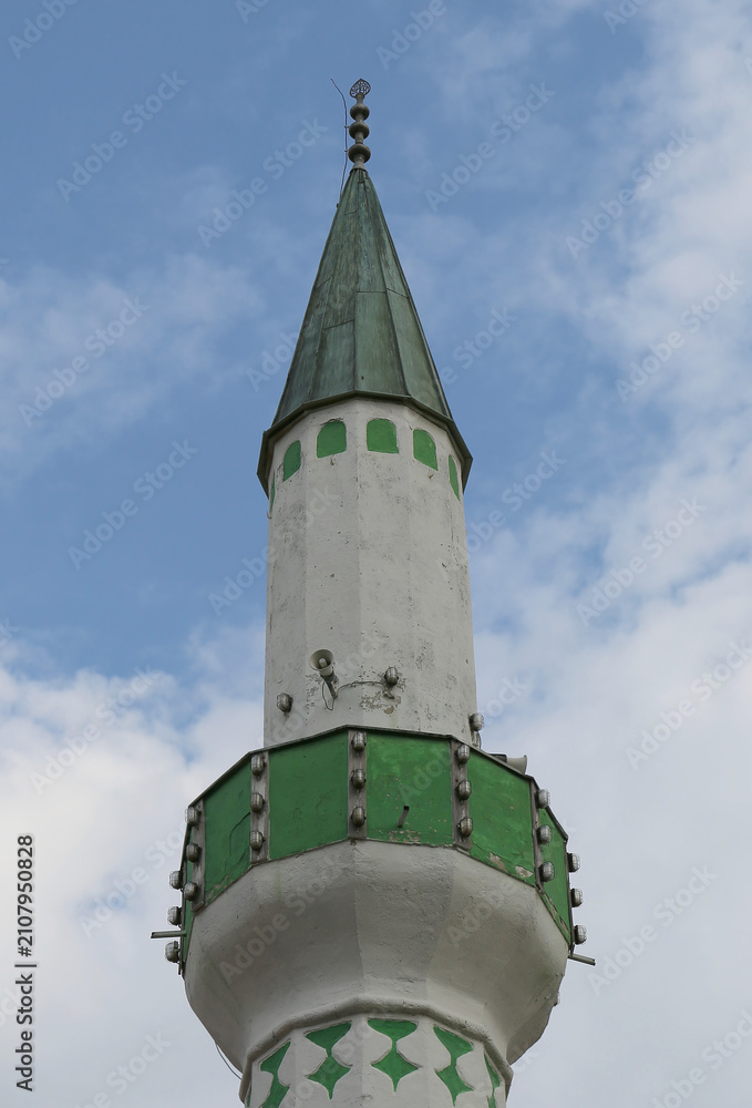 Naklejka premium Short Ottoman era Minaret painted Green and White with Blue Sky Background in Sarajevo, Bosnia and Herzegovina