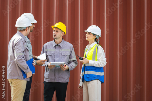 Diverse group of industrial workers and engineers in hard hats meeting in cargo shipping containers, Industrial site managers and construction team talking and planning work at container yard