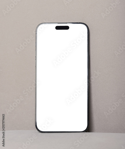 Blank smartphone mockup on beige background. Vertical mobile phone with white screen and minimal studio setup. Ideal for app design, advertising, and product presentation..