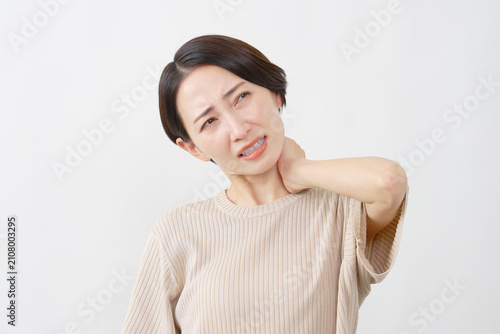 白背景で首の痛みに苦しむ40代女性