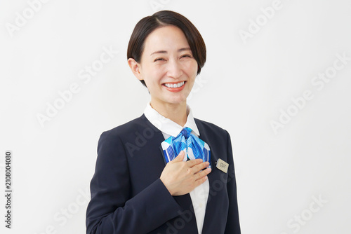 Fotografie 白背景で胸に手を置く笑顔の40代女性スタッフ