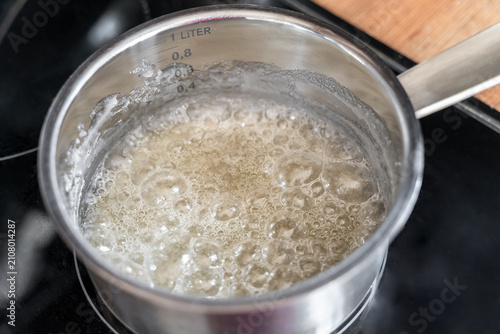 Sugar melting in pot for caramel making with bubbles forming on surface, cooking and confectionery