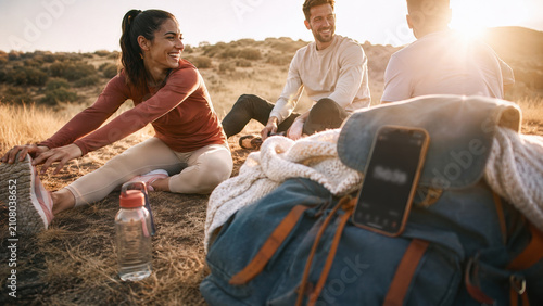 Friends stretching on picnic blanket outdoors at sunset