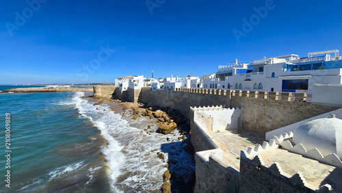 Scenic view of the historic fortified sea walls and whitewashed houses of Asilah medina along the Atlantic coast in Morocco on a sunny day