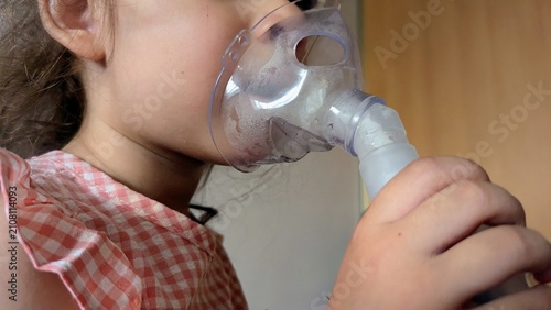 child doing an inhalation procedure using a nebulizer mask. Concept of treating respiratory diseases, asthma, bronchitis, or colds at home.
