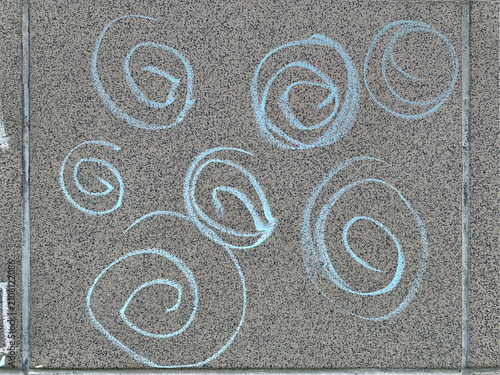 Abstract background of light blue chalk spirals and hand-drawn loops on a grey textured stone wall facade