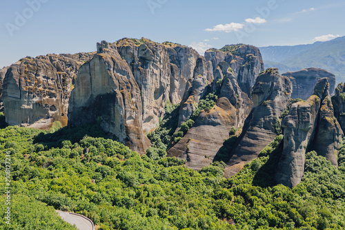 High angle aerial view of massive rock formations rising above green valley forest landscape in famous Meteora UNESCO heritage region near Kalambaka Greece
