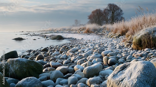 Snow Covered Rocky Coastline by the Sea Under a Clear Blue Winter Sky with Ocean Waves and Scenic Coastal Landscape