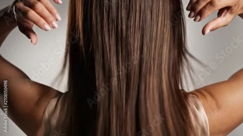 Elegant woman showing her long, smooth, and shiny brown hair from behind