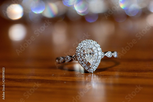 Fotografie Pear-cut diamond engagement ring resting on a wooden tabletop, symbolizing commitment, proposals, romance, and the beginning of a lifelong partnership