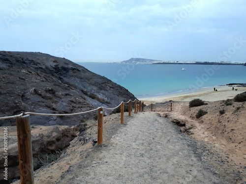 Canvas Print Coastal path descending towards Papagayo Beach with turquoise Atlantic waters, L