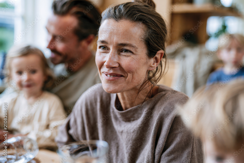 Obraz premium A joyful woman smiles brightly during a family gathering, engaging in laughter and meaningful conversations that illustrate the importance of family bonds and shared moments.