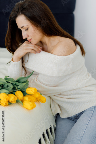 Woman with Yellow Tulips in Sweater. Cozy Bedroom Pose