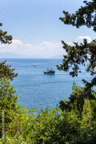 Corfu pirate ship sailing Aegean sea framed by trees